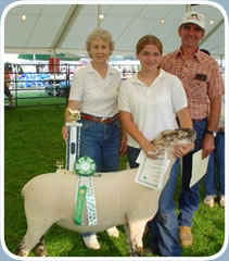 A family poses at a 4-H competition with their daughter’s prizewinning sheep.