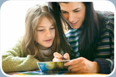 A mother and daughter sign postcards together.