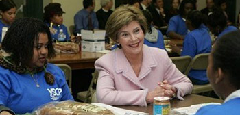 Photo of Mrs. Laura Bush sitting with students at a table with loaves of bread.