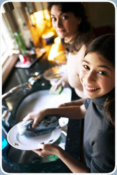 A mother and daughter clean dishes together in their kitchen.