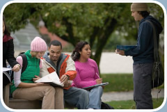 A group of youths sit outside reviewing a homework assignment.