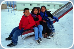 Four Native American youths sit on a playground slide in winter.