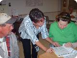 Donnie Edwards, Kathy Graf, and Donna Carter look at insurance documents