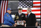 President George W. Bush is presented a piece of the flight deck of the USS Intrepid by Mike Hallahan, left, president of the United War Veterans Council of New York, also joined by military aide U.S. Navy Lt.Cmdr. Clay Beers, during the rededication ceremony Tuesday, Nov. 11, 2008, for the Intrepid Sea, Air and Space Museum in New York. White House photo by Eric Draper