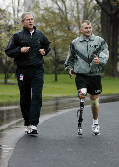President George W. Bush runs with U.S. Army Staff Sergeant Michael McNaughton, of Denham Springs, La., on the South Lawn of the White House Wednesday, April 14, 2004. The two met January 17, 2003, at Walter Reed Army Medical Center, where SSgt. McNaughton was recovering from wounds sustained in Iraq. The President then wished SSgt. McNaughton a speedy recovery so that they might run together in the future. White House photo by Eric Draper