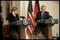 Chancellor Angela Merkel of Germany, adjusts her earpiece as President George W. Bush begins his remarks during a joint press availability Friday, Jan. 13, 2006, in the East Room of the White House. White House photo by Eric Draper