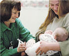 Healthcare provider vaccinating a baby in woman's arms