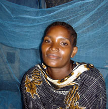 Zanzibari mother sitting under her newly aquired mosquito net which she shares with her newborn baby.