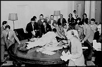 Reporters jump over tables in the White House to pick up press releases about the Japanese surrender, August 14, 1945.