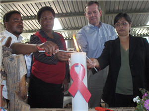 Secretary Leavitt and others lighting a candle with an AIDS ribbon on the front