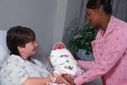 photo of nurse handing baby to mother