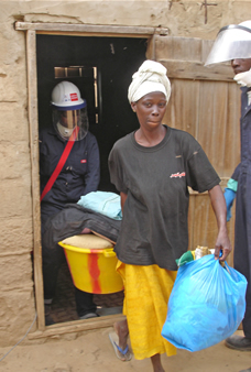 Photo of group supervisor Khoudia Sall (left) and a sprayer helping resident Seynabou Fall remove her household effects in preparations for the second-round of indoor residual spraying in Mbagam, Senegal.