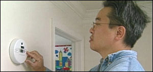 Photo: A man checking a battery-operated carbon monoxide detector