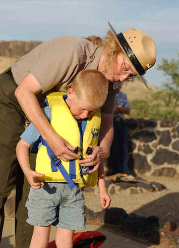 Ranger helping young boy with life jacket