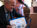 Photo of Rear Adm. Ziemer distributing an LLIN to a young girl who just received two vaccinations, vitamin A, and de-worming medication. (click here to see more)