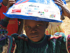 Photo of child holding up a long-lasting insecticide-treated bednet (LLIN) provided through a public-private partnership.