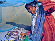 Photo of a woman and her newborn, just 25 days old, under a Long-Lasting Insecticide Treated net.