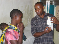 At the Kibiti health center in Tanzania, a health worker explains the infant dosage of Coartem®, a lifesaving anti-malarial drug, for a mother to give to her child.