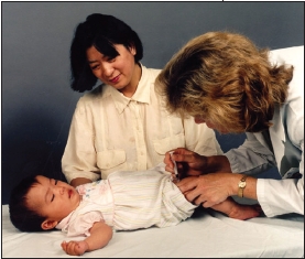 Doctor examines baby, mother looks on