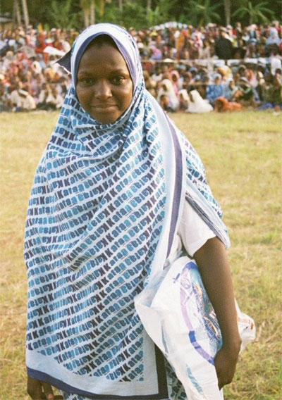 Photo of a young mother draped with a Kataa Malaria hijab, smiling after receiving a net.