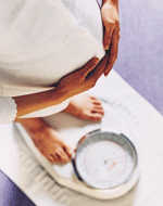 Pregnant woman weighing herself.