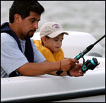 Photo: A father and son wearing appropriate safety equipment for fishing on a boat