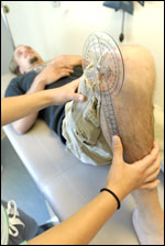 Photo: A physical therapist measuring the degree of movement in a patient's leg.