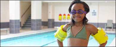 Photo: A girl wearing swim goggles and floaties.