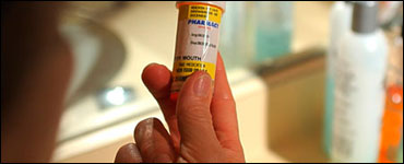 Photo: A person reading the label on a pill bottle.