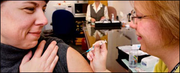 Photo: A woman receiving a vaccine from a healthcare professional.