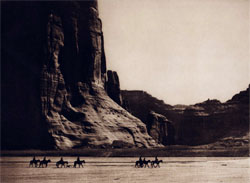 Horses and riders going through a canyon