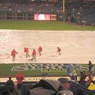 Workers place a rain tarp on the field in Philadelphia
