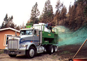 Photo of a crew hydromulching a hillside behind a home.