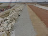 Topping out of left abutment.  Note different zones of material used to build the embankment.  From left (downstream) to right (upstream) in picture: Zone 5 protection stone, Zone 3 gravel filter, Zone 2 sand filter, Zone 1 clay core, Zone 4 rock filter and Zone 5 protection stone. (March 2002)