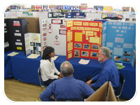 Bob Walker (back to camera) and Rick Andre talk to a student about her Hollenbeck Science Fair project. 