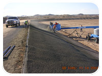 Workers apply 3 inches of shotcrete along a steel reinforced slope to prevent erosion.