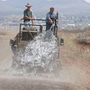 Dust mitigation on U.S. Border Patrol road; trailer-mounted hydroseeder pulled by high-mobility multi-wheeled vehicle (click to view larger image)
