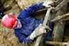 U.S. Marine Corps Pfc. John Michaud slides under a steel grate through the mud to exit a tunnel of debris at the Naval Support Center, Indian Head, Md., Dec. 18, 2008. Michaud was working with other Marines and sailors inside the tunnel to free a mock survivor during the collapsed building exercise. 