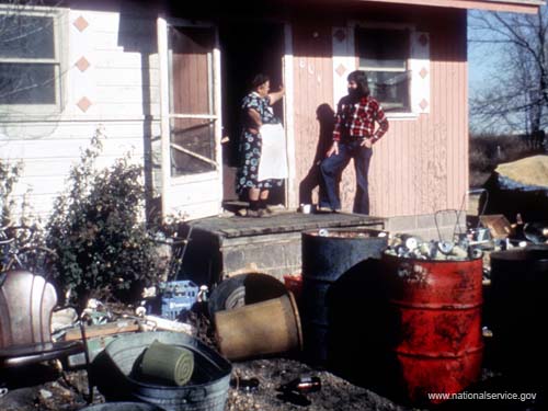 VISTA member Ned Murray discusses a housing problem in 1974 with a resident in this Laurel, Kansas, community in an effort to get the family into more comfortable and healthy quarters.