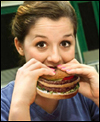 photo of woman eating large hamburger
