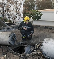 An Israeli firefighter looks at the damage made after a rocket fired from Lebanon hit a building in the northern Israeli coastal town of Nahariya, 08 Jan 2009