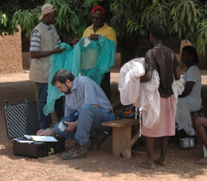 Steve Smith, CDC chemist, uses a portable X-ray fluorescence analyzer to measure the insecticide content of a treated bed net in rural Ghana. (Courtesy Joel Selanikio, DataDyne).