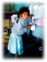 Niña boliviana utilizando el Sistema de Agua Segura para obtener agua potable segura.