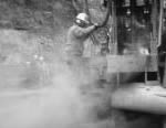 Trabajador que opera una perforadora en una nube de polvo 