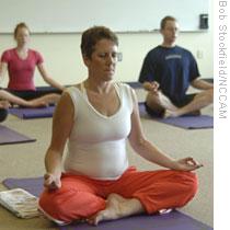 Participants in a yoga class meditate in the lotus pose