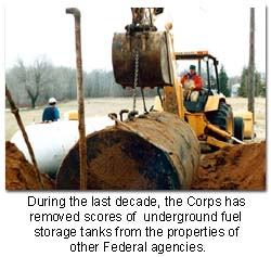 Photo of a man on a crane. There is a man and a tank in the background.