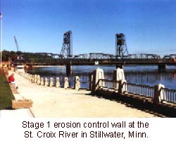 A photo of a cement path lined with a railing. There is a bridge in the background.