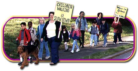 Kids and parents walking together, carrying signs encouraging walking