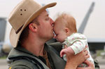 Navy Lt. Cmdr Sean Cushing kisses his daughter at Atsugi, Japan, May 22, 2004, after his return from a deployment with Strike Fighter Squadron 195. VFA-195 is assigned to Carrier Air Wing 5 aboard the conventional aircraft carrier USS Kitty Hawk.