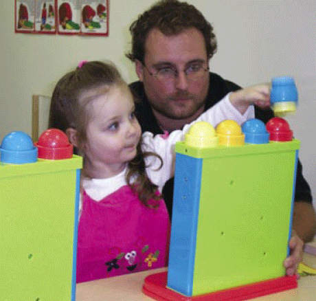 photo of a man and child; child is playing with a toy